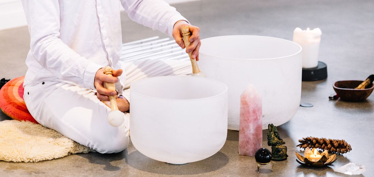 Sound bath meditation with singing bowls - a person lying peacefully while surrounded by crystal singing bowls